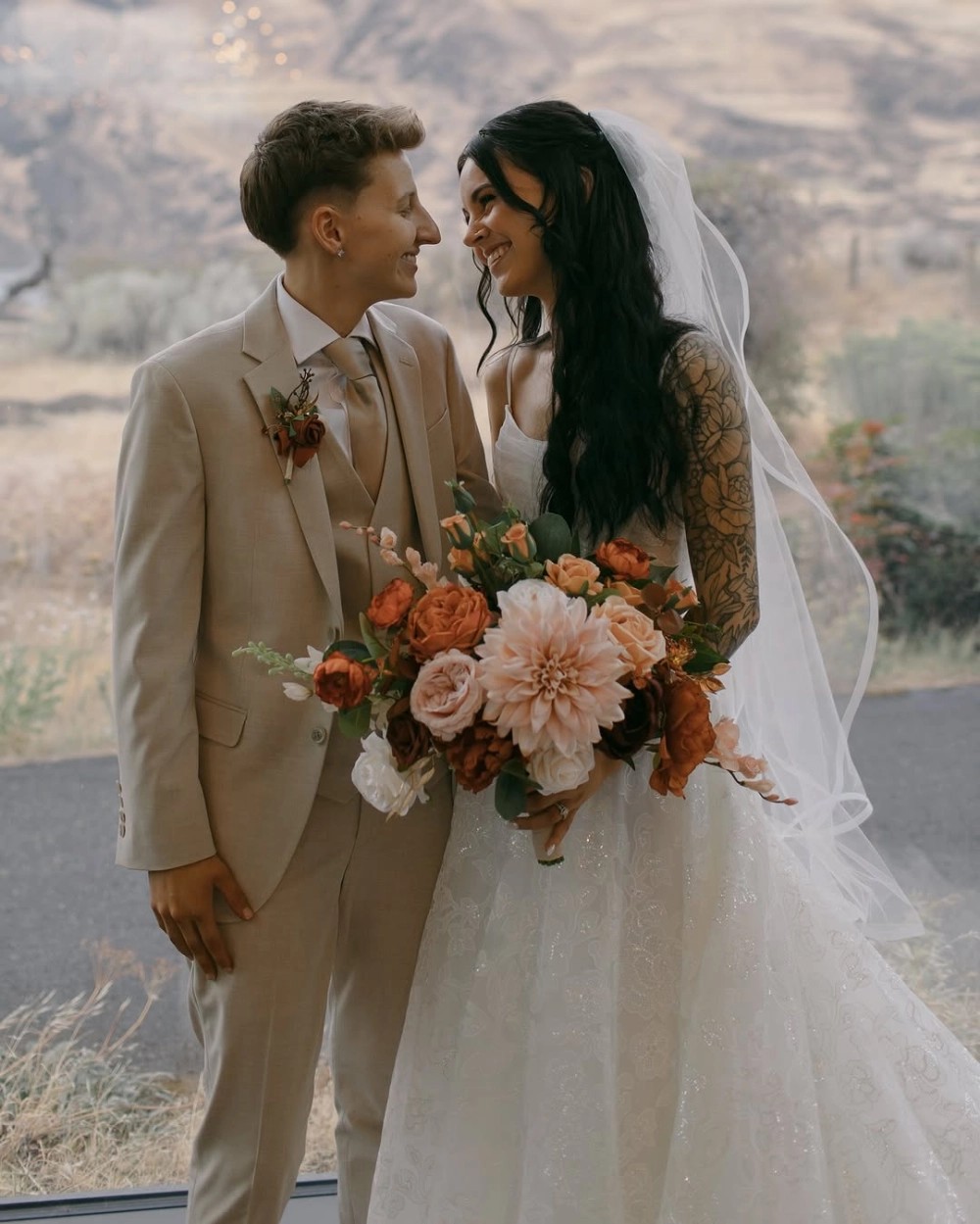 Couple wearing white gowns and beige suit